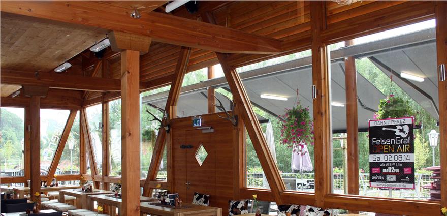 Rustic restaurant interior with exposed timber framework, large windows, and antler wall decor.