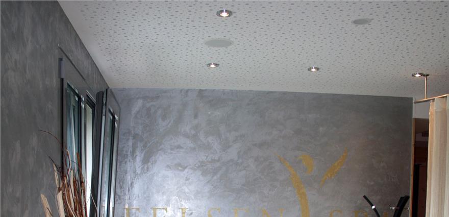 Modern interior with gray textured wall, dotted ceiling, and gold lettering on the wall.