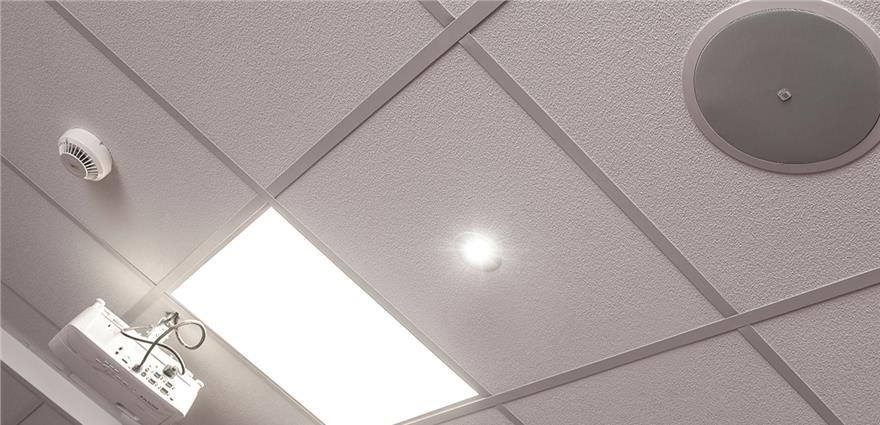 Ceiling with square acoustic tiles, recessed light, sprinkler, and a ceiling-mounted projector.