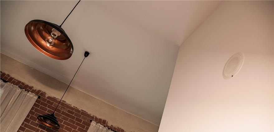 Industrial interior with copper pendant lights hanging over a brick wall and white ceiling.