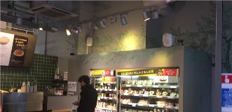 Cafe interior with a salad display case and customers selecting meals.