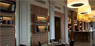 Modern restaurant interior with pink-lit shelving, white walls, and wooden dining tables.