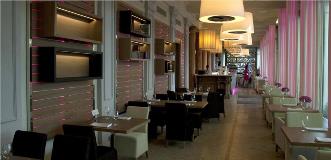 Modern restaurant interior with a long dining hall, wall shelves, pink accent lighting, and a back bar.