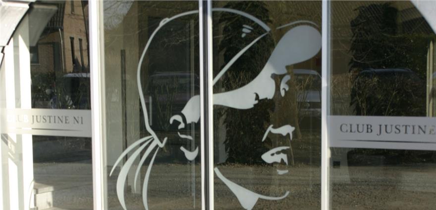 Frosted glass doors with a stylized profile of a tennis player and the text “Club Justine N1.”