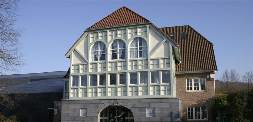 Large building with red-tiled roof and pale green arched windows on the front facade.