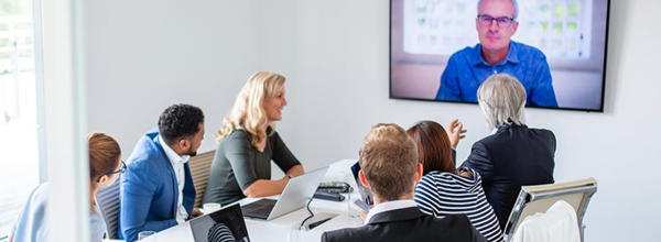 Team in conference room using video conferencing to meet with remote colleague on wall display