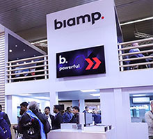 Biamp trade show booth with digital signage and attendees exploring professional AV solutions