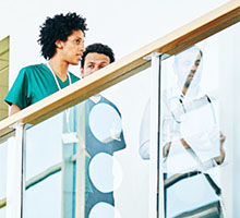 Healthcare professionals talking in a modern hospital corridor behind glass railing