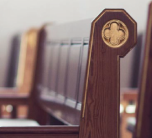 Close-up of wooden church pew with decorative carved end in a quiet sanctuary