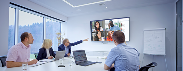 Business team in conference room using video conferencing for hybrid meeting with remote colleagues on display