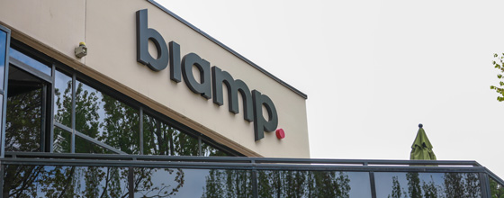 Exterior of a building with large 'biamp.' signage above reflective glass windows.