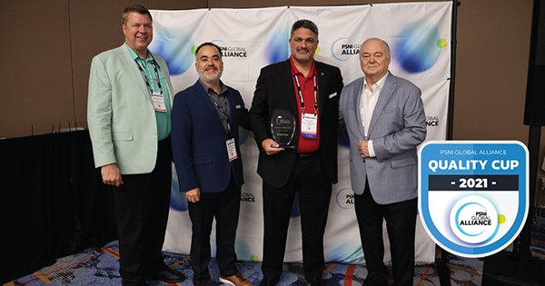 Biamp team members receiving PSNI Global Alliance Quality Cup 2021 award, posing with trophy in front of branded event backdrop.