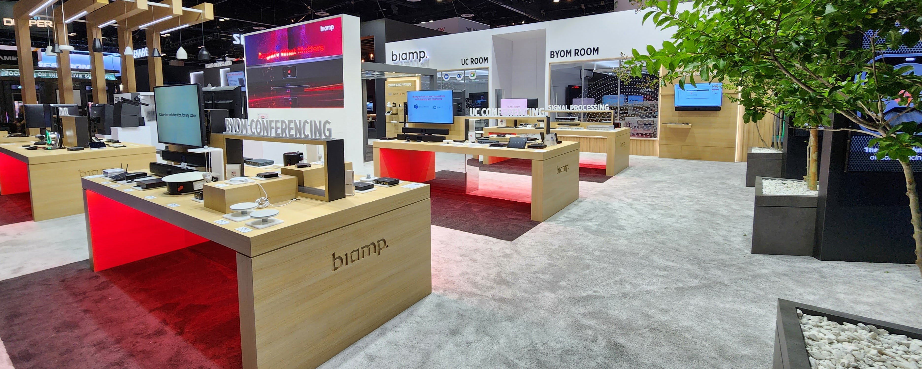 Biamp trade show booth showcasing conferencing, BYOM, and signal processing solutions with interactive product displays and modern, open design.