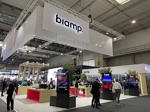 Biamp exhibition booth at a trade show, showcasing pro AV solutions with product demos, digital displays, and attendees exploring the stand.