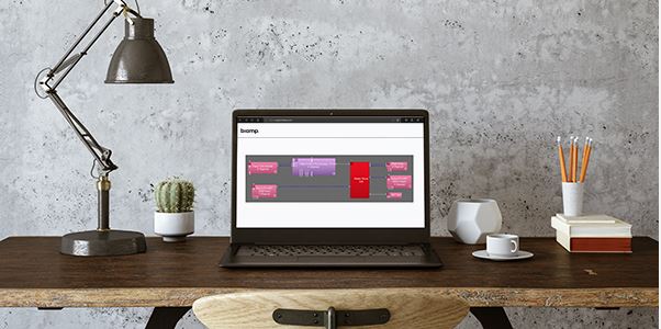 Laptop on a stylish home office desk displaying Biamp software interface, illustrating remote AV system management and workspace design.