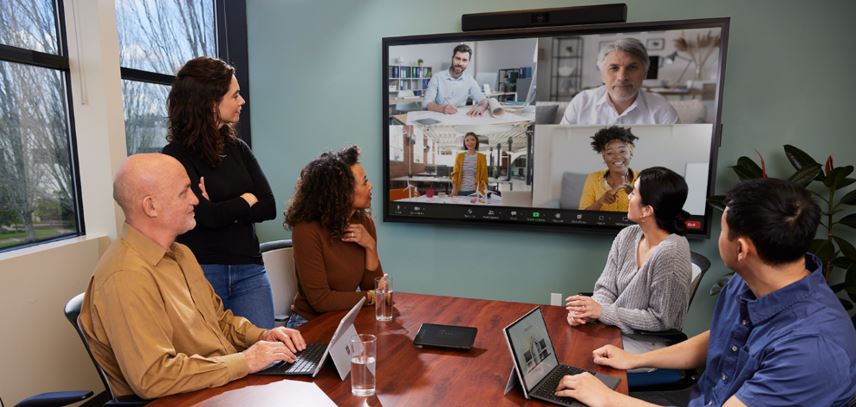 Hybrid meeting in a conference room with in‑person team collaborating via large display video call, showcasing modern Zoom‑enabled workspace.