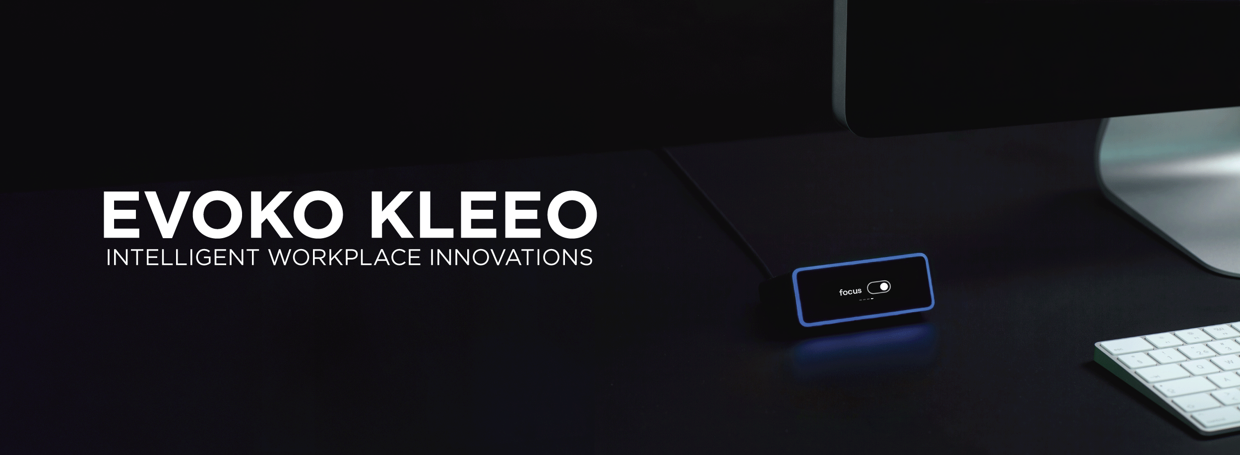 Evoko Kleeo desk availability indicator illuminated on a dark workstation beside a keyboard, with text “Evoko Kleeo – Intelligent Workplace Innovations.”
