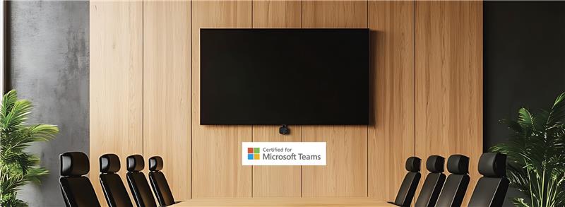 Modern boardroom with long table, black chairs, large wall‑mounted display and “Certified for Microsoft Teams” logo.