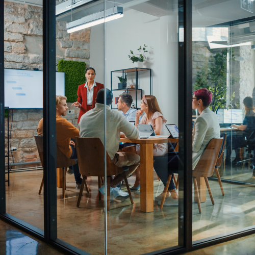 Image of a group of workers in a conference room around a conference table.