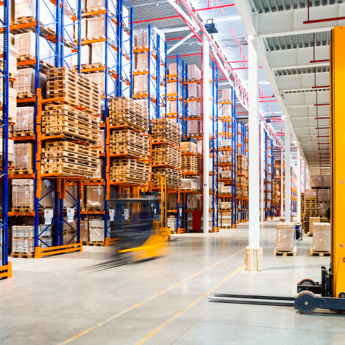 Image of a warehouse with forklifts moving.